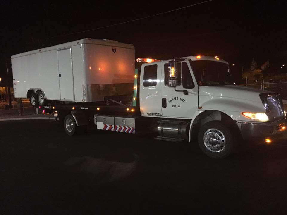 Secured Rite Towing truck hauling an enclosed trailer at night