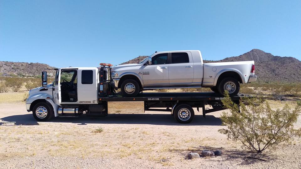 Secured Rite Towing flatbed truck carrying a pickup in the Arizona desert
